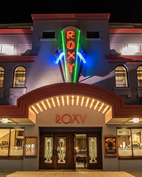 Photo of the Roxy Cinema building lit up at night.